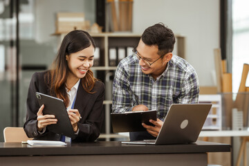 A middle-aged businessman, a young businesswoman, and Asian individuals are collaborating at desks....