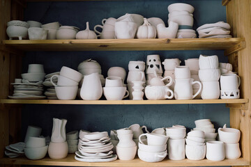 No people shot of stacks of handmade earthenware on wooden shelves in pottery workshop
