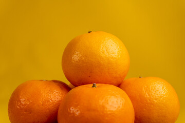 close up of stacked oranges isolated yellow background