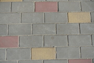 Obraz premium Close view of gray, pink and yellow concrete pavement with stretcher bond pattern