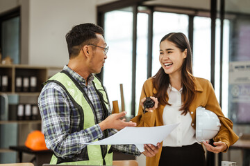 Obraz premium A middle-aged man, a young woman, and other Asian individuals collaborate on architectural engineering for condos and apartments, focusing on sustainable renovation and green energy solutions.