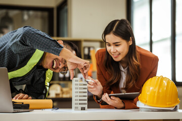 A middle-aged man, a young woman, and other Asian individuals collaborate on architectural...