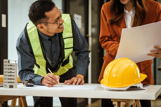 A middle-aged man, a young woman, and other Asian individuals collaborate on architectural engineering for condos and apartments, focusing on sustainable renovation and green energy solutions.
