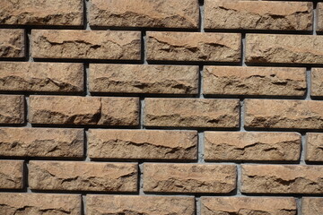Surface of brown split face brick veneer wall with stretcher bond pattern