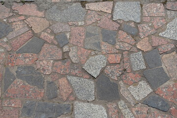 Background - crazy pavement made of multicolored polished granite stone blocks