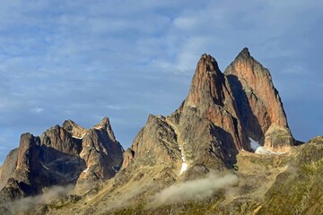 Fototapeta premium the steep, glaciated granite peaks of the western side of the prince christian sound and wisps of fog, in southern greenland, from a cruise ship