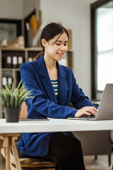 Young woman and other Asian individuals in formal suits working at desks with laptops. They engage in financial tasks including amortization, liquidity analysis, risk assessment, financial modeling.