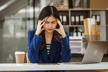 Young woman and other Asian individuals in formal suits work at desks with laptops, addressing concerns such as office syndrome, ergonomics, musculoskeletal disorders, and computer vision syndrome.
