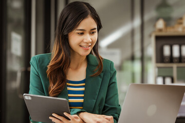 Young woman and other Asian individuals in formal suits working at desks with laptops. They engage in financial tasks including amortization, liquidity analysis, risk assessment, financial modeling.