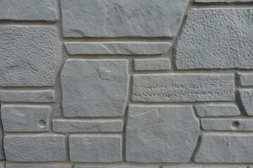 Dusty surface of dark gray concrete brick veneer wall with random layout