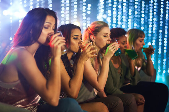 Friends, woman and drinking in nightclub together, night life and fun for celebration or new years party with alcohol shots. Festival, disco lights and social or cocktails, line up group and beverage