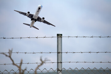 Passenger plane flying behind stainless steel fencing wire. Aviation idea concept. Deported....