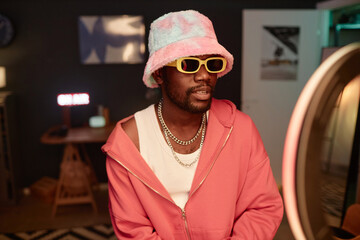 Waist up portrait of trendy Black young man wearing pink outfit and recording videos for social...