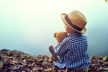 Relax, teddy bear and boy in nature by lake for fun summer vacation, holiday and weekend alone....
