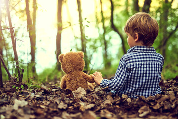 Young boy, teddy bear and comfort in forest for adventure with embrace and support in nature....