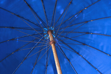 Blue beach umbrella in low angle view. Summer vacation. Shade under parasol.