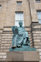 Naklejka premium Statue of David Hume, prominent Scottish philosopher and historian depicted sitting down while holding a tablet and his toe shined by the touch of passersby, Edinburgh, Scotland, UK