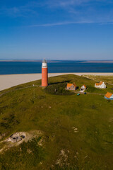 An aerial perspective of a majestic lighthouse standing tall on the sandy shores of Texel,...