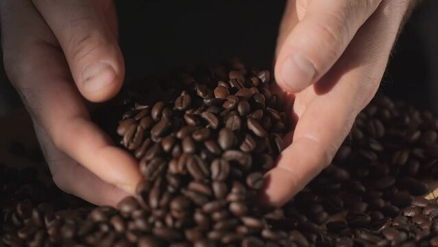 A closeup sequence captures hands delicately handling and releasing aromatic coffee beans in a slow and stylish manner