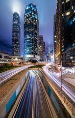 Skyscraper buildings and traffic on road with blurred cars light trails at night, Hong Kong, China