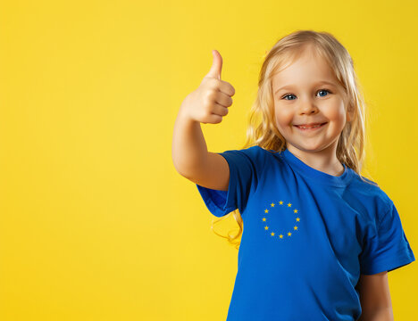 Portrait of a Young Blonde Girl Wearing a European Union Flag T-Shirt on a Yellow Background