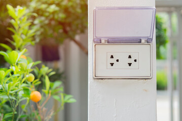 White plug on white wall with a garden in the background, plug socket, electric, plug outlet