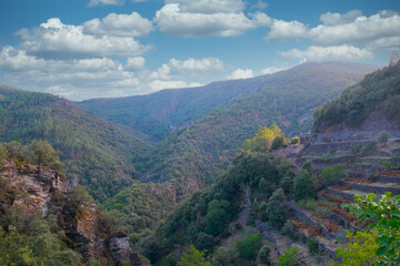 Fototapeta premium A stunning view of a mountain valley showing terraces, lush greenery, and a vibrant sky with clouds