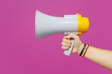 Close up cropped female holding in hand megaphone loud-hailer bullhorn isolated on pastel plain purple color background studio. Pride day June month love LGBTQ concept. Copy space advertising mock up.