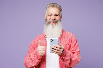 Young fun elderly gray-haired mustache bearded man 50s years old wears pink shirt casual clothes hold use mobile cell phone show thumb up isolated on plain pastel purple background. Lifestyle concept. - Powered by Adobe
