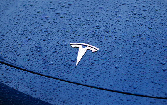 Kyiv, Ukraine. May 30, 2024. Tesla emblem in a close up view with water drops. Brand logo on a blue car hood 
