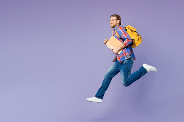 Full body young happy smart boy student wears blue casual clothes backpack bag hold books jump high run fast isolated on plain pastel light purple background. High school university college concept.