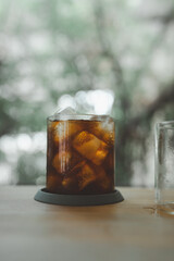 A glass of iced americano with frozen ice cubes on wood table