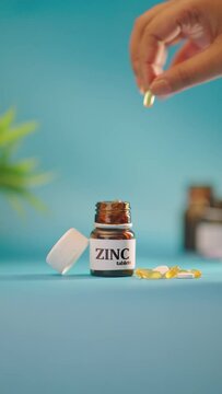VERTICAL VIDEO OF HAND TAKING OUT ZINC TABLETS FROM MEDICINE BOTTLE