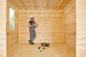 Construction man, builder man construct new wooden home, tiny house style. Spirit level, screw,...