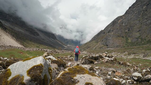 Lonely woman backpacker trekker dressed bright jacket going by mountain valley path on the Mera peak climbing route near Tagnag settlement at cca 4150m. Active people wide mountain valley 4K video.