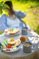 breakfast in the garden in summer food on the table, eggs buns and coffee