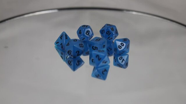 A set of blue dice with black writing including a D20 spinning on a turntable