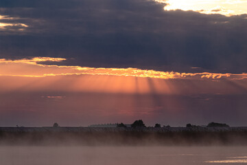 Światło wschodzącego słońca świecące przez chmury © KoLesfot