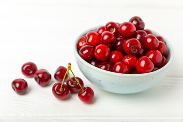 Cherries. Fresh ripe cherries with leaves on a textured wooden background. Fresh sweet organic cherry pile. Berries and fruits. Vegan. Healthy eating. Place for text. Copy space