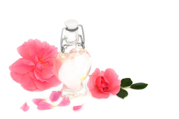 Rosewater for skin care with pink rose flowers on white with heart shaped bottle. Natural product to hydrate skin, treat skin redness, irritation, scars, burns, restore ph balance.