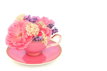 Rose lavender and elder flowers in tea cup on white. Surreal fun food medicinal herbal medicine composition. Flowers have adaptogen relaxation health benefits.