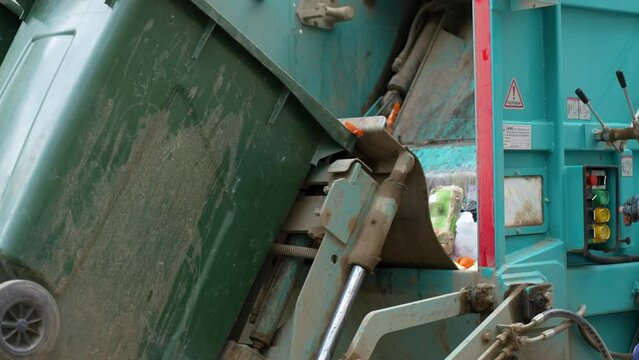 Waste collector loading waste into the garbage truck, close-up
