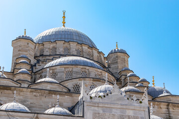 View of the dome and minarets with a blue isolated sky from outside the New Mosque in Eminönü,...