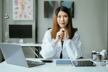 Successful  female doctor sitting at a desk, looking at the camera.