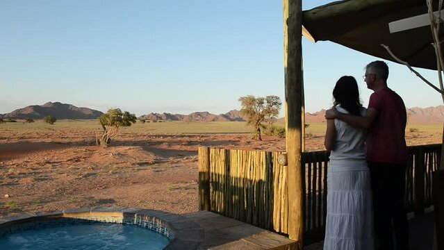 Couple at sunset are watching savana from a safari camp. Namibia