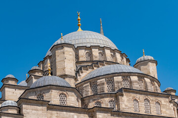 View of the dome and minarets with a blue isolated sky from outside the New Mosque in Eminönü, Istanbul.