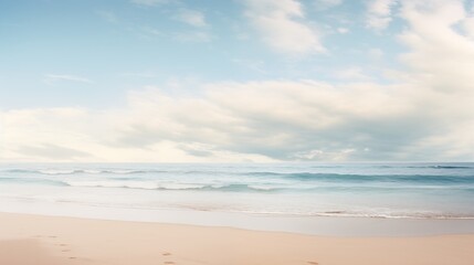 A serene beach scene with gentle waves, a blue sky filled with clouds, and footprints in the sand.