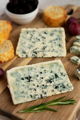 Organic Blue Cheese with Grapes and Olives on a Wooden Board, side view.