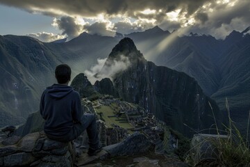 Fototapeta premium A man sitting atop a mountain with a breathtaking view of the valley below, perfect for use in travel or outdoor adventure contexts