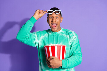 Fototapeta premium Photo of excited cool guy dressed turquoise sweatshirt watching movie enjoy pop corn isolated violet color background